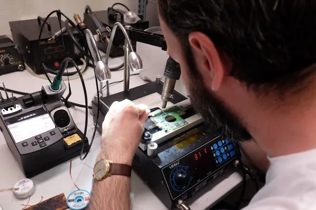 Technik s pájecí stanicí opravuje elektroniku průmyslového média